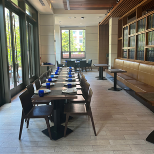 Semi-private dining space with a long table along a corridor with chairs and place settings.