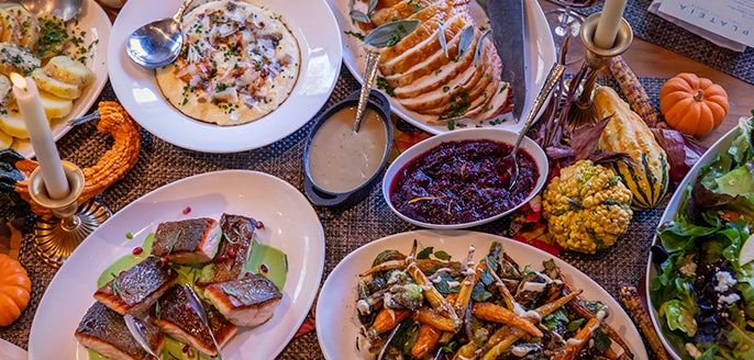 A table filled with Thanksgiving dishes including turkey, mashed potatoes, cranberry sauce, and roasted vegetables
